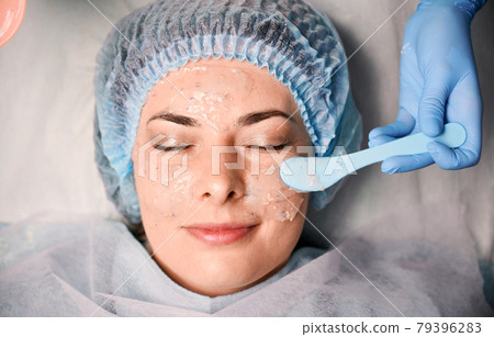 Cosmetologist hand applying cosmetic mask on woman face. 79396283