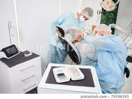 Dentist using dental implant machine during implantology procedure. 79396393
