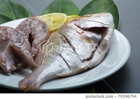 Fresh raw fish on white plate with green leaf and lemon Fresh raw fish on white plate with green leaf and lemon 79396704