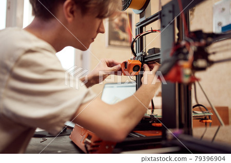 Young man set up 3d printer 79396904