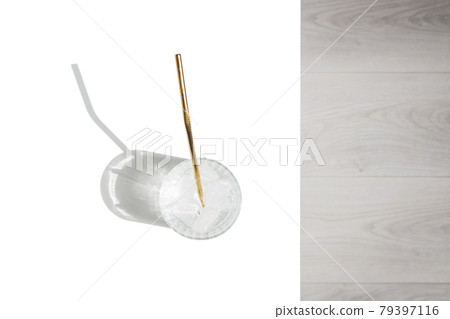 Transparent glass of water with reusable metal eco straw in sunlight with shadows. 79397116