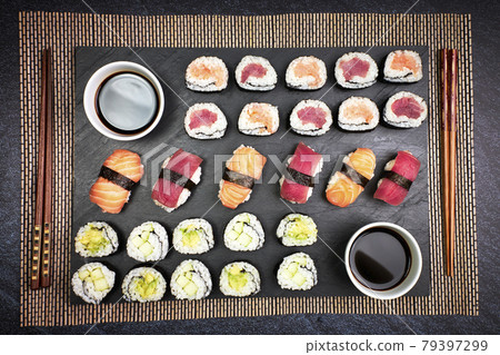 Top view of fish sushi and vegetable sushi with chopsticks and soy sauce on a blackboard. Japanese culture 79397299