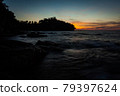 Vivid sunset sky waterscape and silhouette forest island 79397624