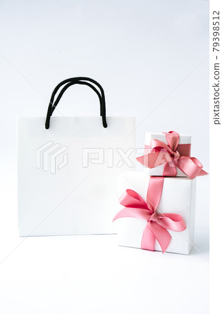 Blank paper white bag and two gift present boxes with pink ribbon on white background. Black friday sale. Shopping concept. Mockup of paper shopping bag 79398512