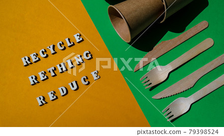 RECYCLE RETHING REDUCE text Wooden forks and paper cups with plates on color background. Eco friendly disposable tableware. Used in fast food, restaurants, takeaways, picnics. No plastic 79398524