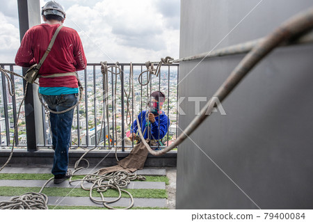 The Builder is hanging on the ropes working on high building. The Builder is hanging on the ropes working on high building. 79400084