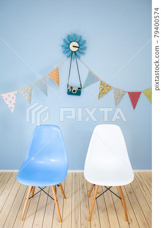 淺藍色壁藍色時鐘和彩色花環和淺藍白相間的 Eames 椅子 79400574