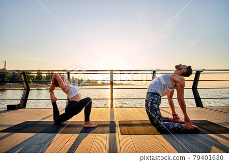 Couple doing practicing yoga together on nature outdoors . Morning exercises at the sunrise. 79401680