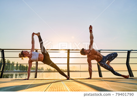 Couple doing practicing yoga together on nature outdoors . Morning exercises at the sunrise. 79401790