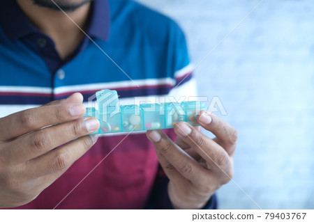 man's hands taking medicine from a pill box  79403767