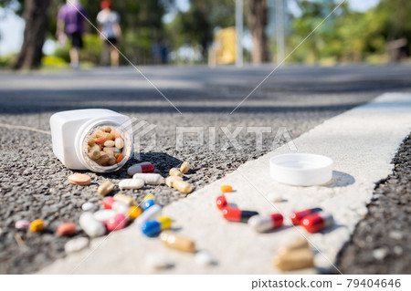 Plastic bottle of medication dropped on the street outdoor,drug scattered on the floor,jar of medicine with different pills tablets and capsules fall on the ground,should not be consumed,dirty unclean Plastic bottle of medication dropped on the street outdoor,drug scattered on the floor,jar of medicine with different pills tablets and capsules fall on the ground,should not be consumed,dirty unclean 79404646