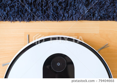 Top view of wireless robot vacuum cleaner cleaning the floor near the carpet and plant Top view of wireless robot vacuum cleaner cleaning the floor near the carpet and plant 79404668