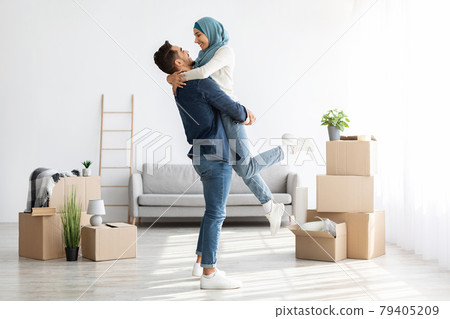 Ecstatic muslim family cuddling while moving to new house 79405209