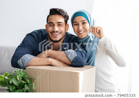 Key chain in smiling muslim couple hands, moving concept Key chain in smiling muslim couple hands, moving concept 79405335