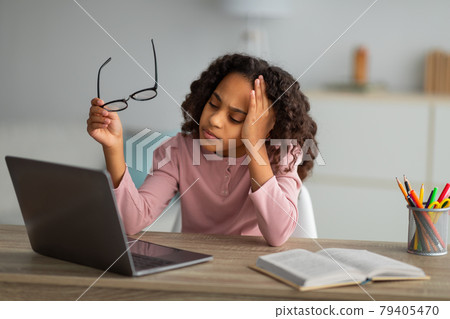 Tired student. African american schoolgirl studying online on laptop at home, exhausted from looking at screen Tired student. African american schoolgirl studying online on laptop at home, exhausted from looking at screen 79405470