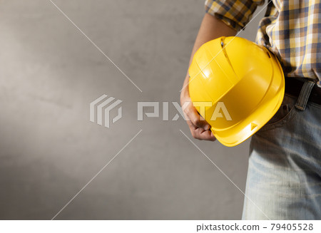 Man worker holding construction helmet near plater wall. Male hand and construction tools 79405528