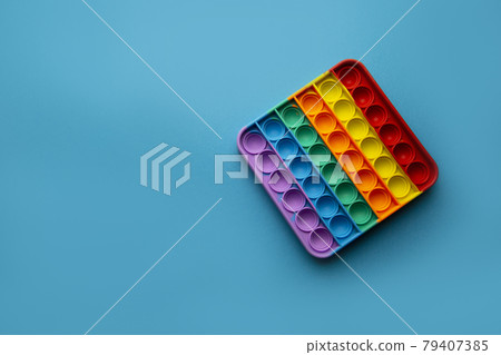 Sensory color trendy pop it stress reliever toy isolated on blue background Sensory color trendy pop it stress reliever toy isolated on blue background 79407385