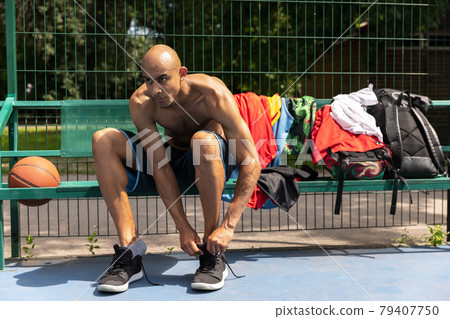 Young strong man, male basketball player at street public stadium, sport court or palyground outdoors. Concept of healthy active lifestyle, motion, hobby. Young strong man, male basketball player at street public stadium, sport court or palyground outdoors. Concept of healthy active lifestyle, motion, hobby. 79407750