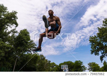 Young man, muscular african male basketball player playing basketball at street public stadium, sport court or palyground outdoors. Summer sport games. Young man, muscular african male basketball player playing basketball at street public stadium, sport court or palyground outdoors. Summer sport games. 79407862