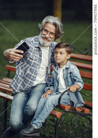 Grandfather with grandchild sitting in a summer park Grandfather with grandchild sitting in a summer park 79407998