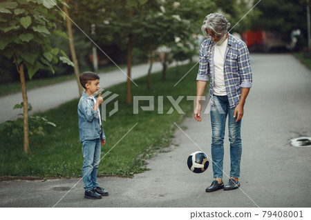 Grandfather with grandchild walking in a summer park Grandfather with grandchild walking in a summer park 79408001