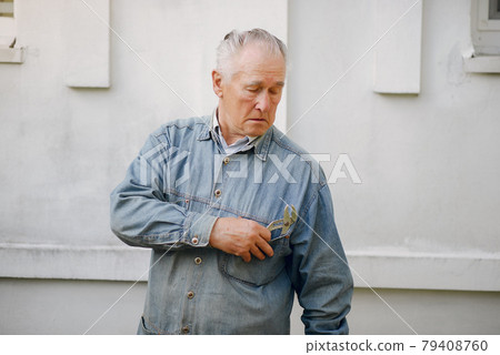 Old man standing near building with a repair tools 79408760