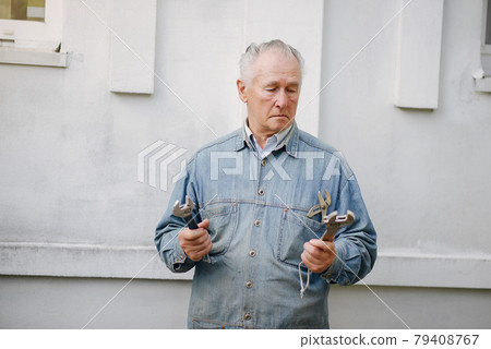Old man standing near building with a repair tools 79408767