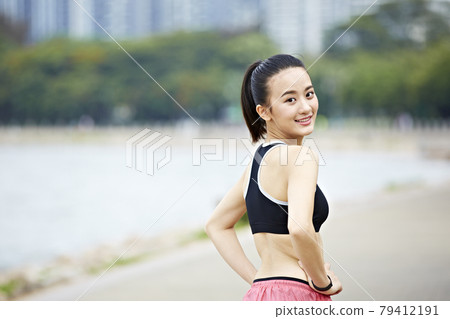 young asian woman runner turning to look at camera before running young asian woman runner turning to look at camera before running 79412191