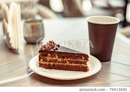 Chocolate multilayer cake or piece of cake on an eco-friendly paper plate in a street cafe 79413698