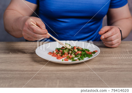 Salad with cucumber, tomato and green onions on a plate. A man holding a plate of salad Salad with cucumber, tomato and green onions on a plate. A man holding a plate of salad 79414020