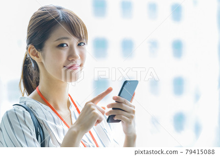 A young business woman operating a smartphone in the office A young business woman operating a smartphone in the office 79415088