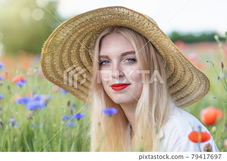 Portrait of beautiful  young woman in straw hat is posing  outdoors 79417697