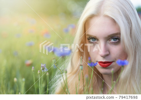 Portrait of beautiful  young woman posing in cornflower meadow 79417698