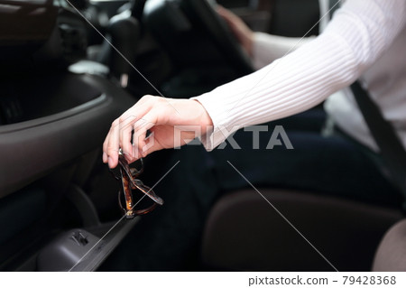 A woman's hand sitting in the driver's seat taking out small items from the dashboard A woman's hand sitting in the driver's seat taking out small items from the dashboard 79428368