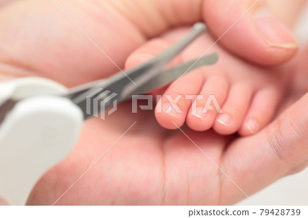 Mom cutting newborn toenails 79428739
