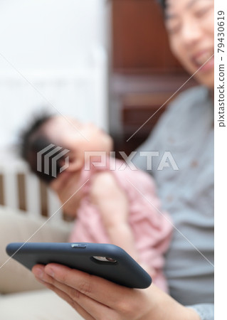 Daddy holding a newborn baby and raising a smartphone 79430619