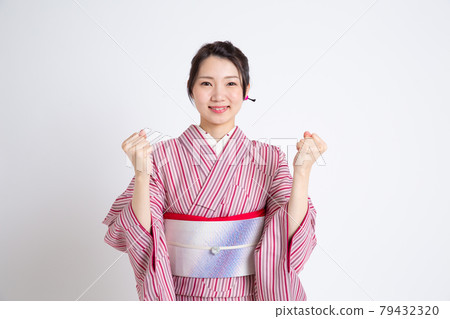 一個年輕的日本女人戴著小冠,做著膽子的姿勢 一個年輕的日本女人戴著小冠,做著膽子的姿勢 79432320