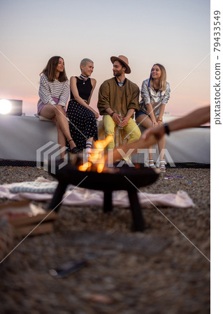 Friends by a fireplace on the rooftop at sunset 79433549