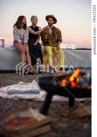 Friends by a fireplace on the rooftop at sunset 79433565