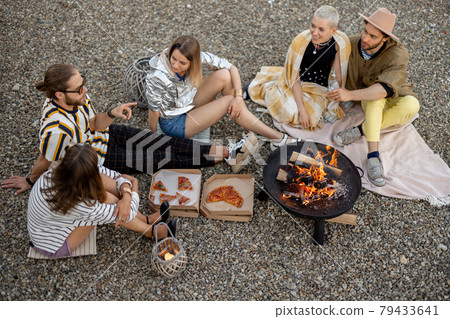 Friends sitting by the fireplace outdoors 79433641