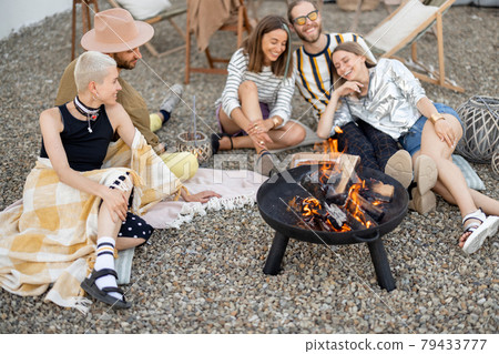 Friends sitting by the fireplace outdoors 79433777