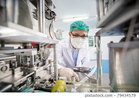 Mid adult male engineer examining machine part on a production line in a factory. Mid adult male engineer examining machine part on a production line in a factory. 79434579