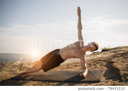 Sporty young man with naked torso doing exercises for abs 79435133