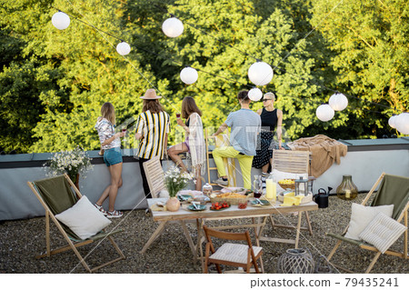 Young stylish friends having a festive dinner on the roof terrace Young stylish friends having a festive dinner on the roof terrace 79435241