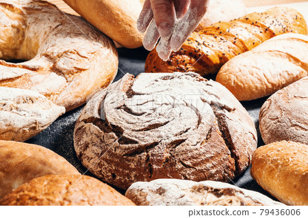 Baking close-up. Appetizing buns sprinkled with flour on a black wooden table. Bakery products 79436006