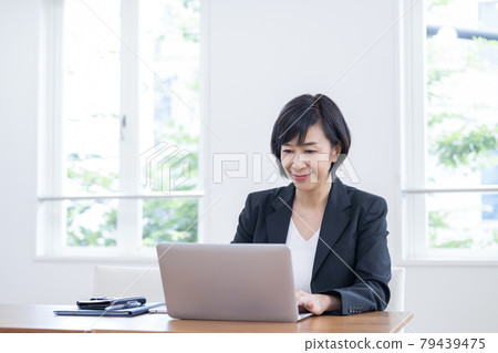 Business A middle-aged woman who works on a personal computer 79439475