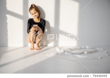 Little girl sitting with smart phone in gymnastics class 79440495