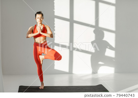 Athletic woman balancing in yoga pose indoors Athletic woman balancing in yoga pose indoors 79440743