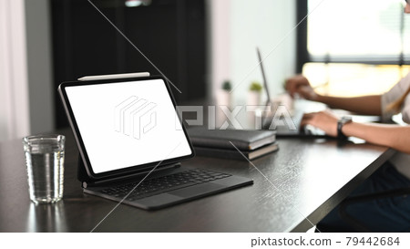 Stylish workspace with with screen computer tablet, water glass and notebooks. 79442684