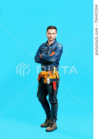 Full length portrait of confident handsome male construction worker staying over blue background 79445504